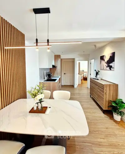 Modern dining area with elegant lighting and open kitchen layout in stylish apartment.