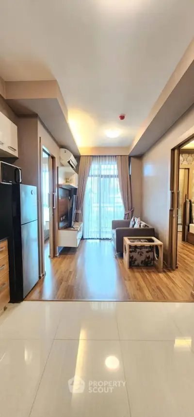 Modern living room with wooden flooring, stylish furniture, and large windows for natural light.