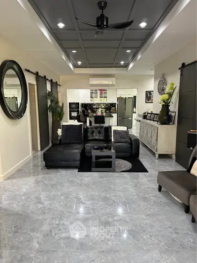 Spacious modern living room with sleek black furniture and open kitchen layout, perfect for entertaining.