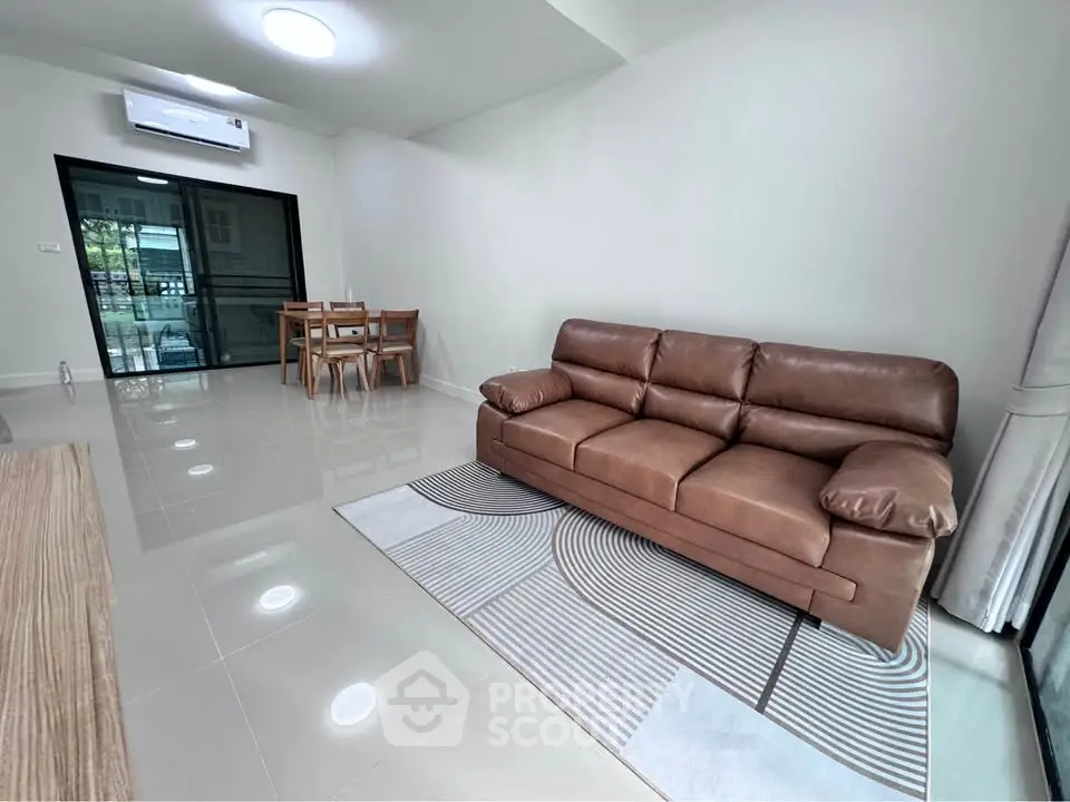 Spacious living room with modern leather sofa and dining area, perfect for relaxation and entertaining.