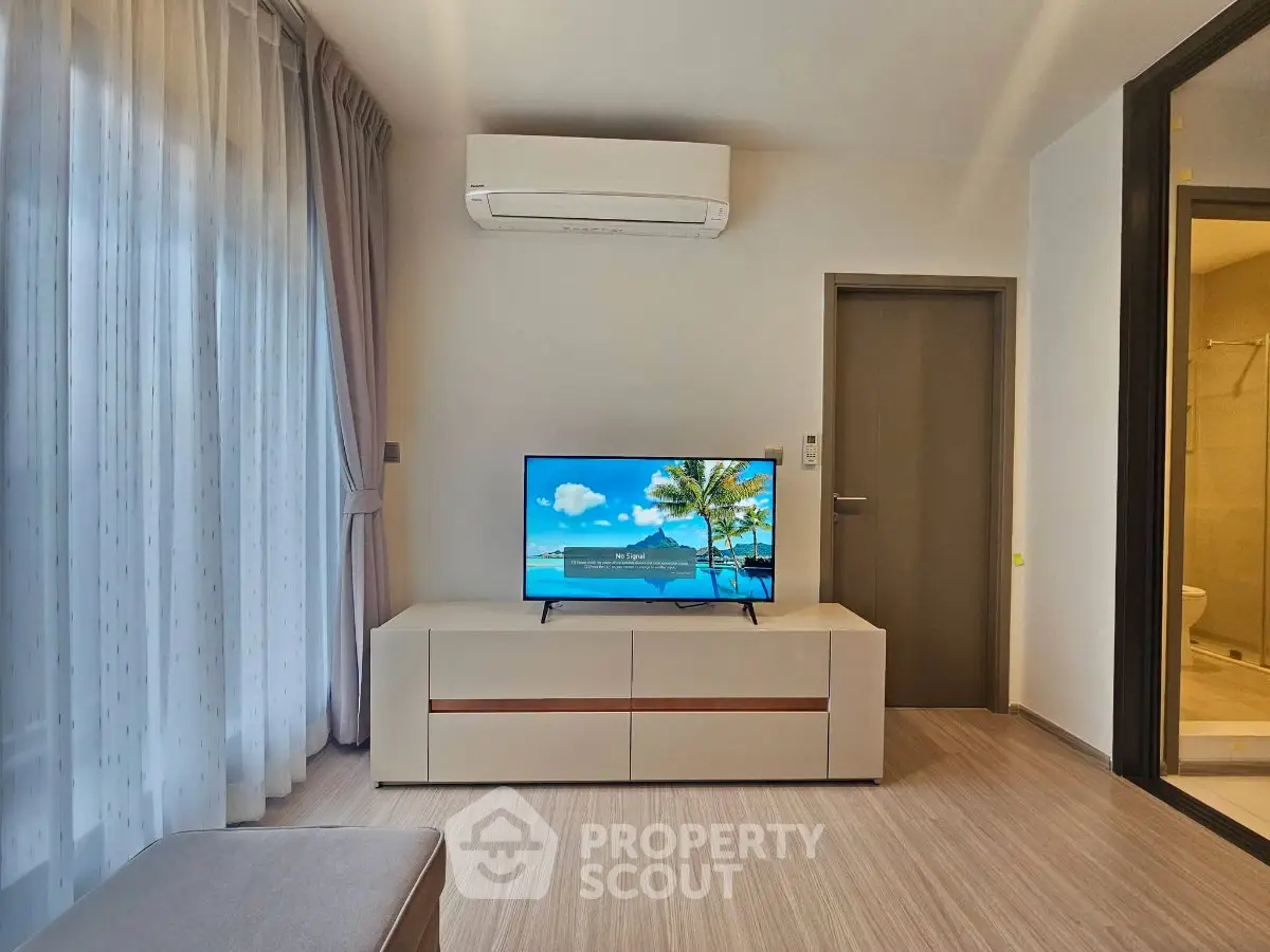Modern living room with sleek TV setup and air conditioning, featuring elegant curtains and minimalistic design.