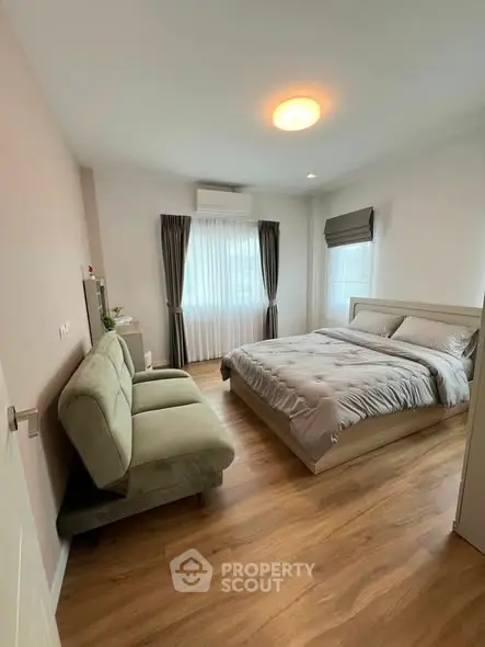 Cozy bedroom with modern decor and natural light, featuring a comfortable bed and stylish sofa.