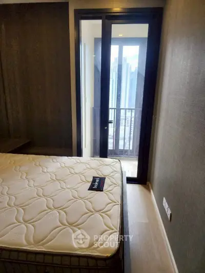 Modern bedroom with balcony access and city view, featuring a comfortable mattress and sleek design.