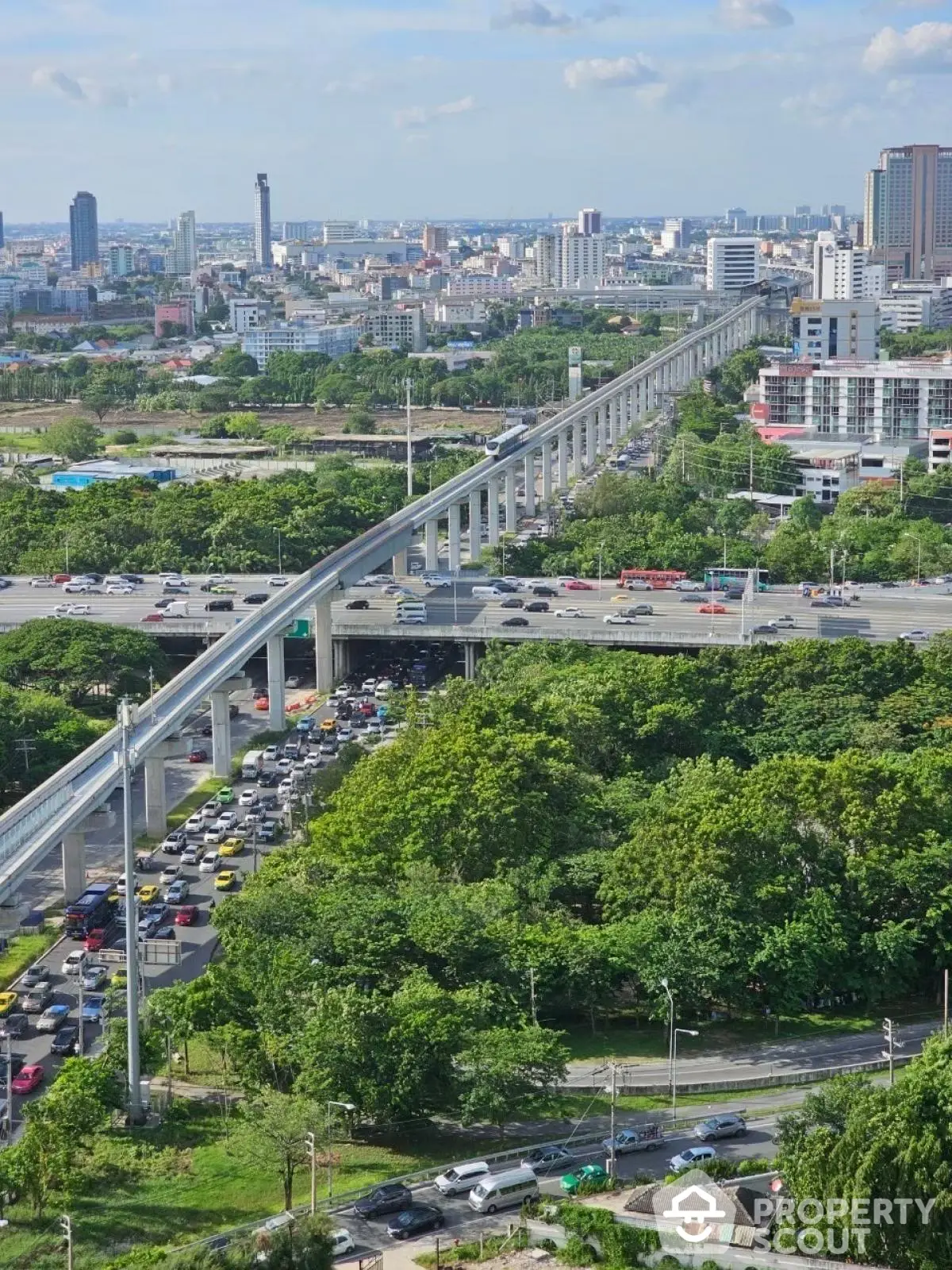 Stunning cityscape view with elevated train tracks and lush greenery, perfect for urban living.