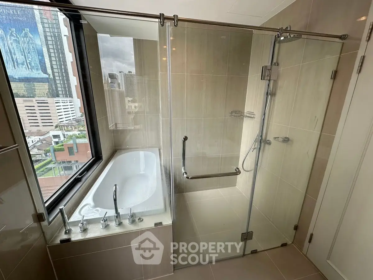 Luxurious bathroom with city view, featuring a glass shower and bathtub.