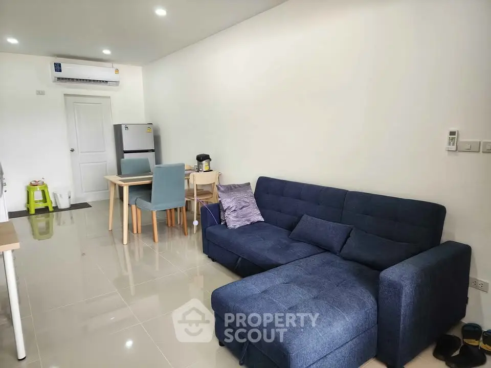 Modern living room with sleek furniture and dining area in open layout apartment.