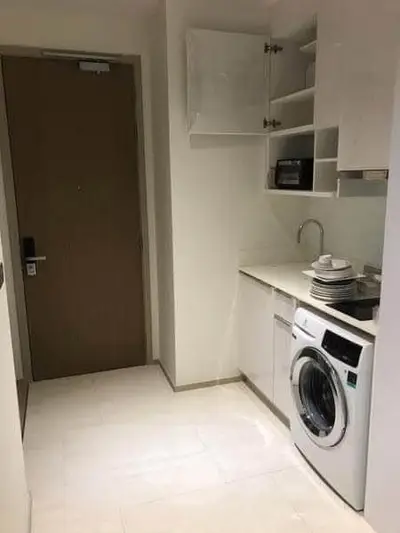 Modern laundry area with washing machine and storage cabinets in sleek apartment.