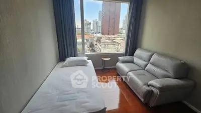 Cozy bedroom with city view, featuring a single bed and comfortable sofa, perfect for urban living.