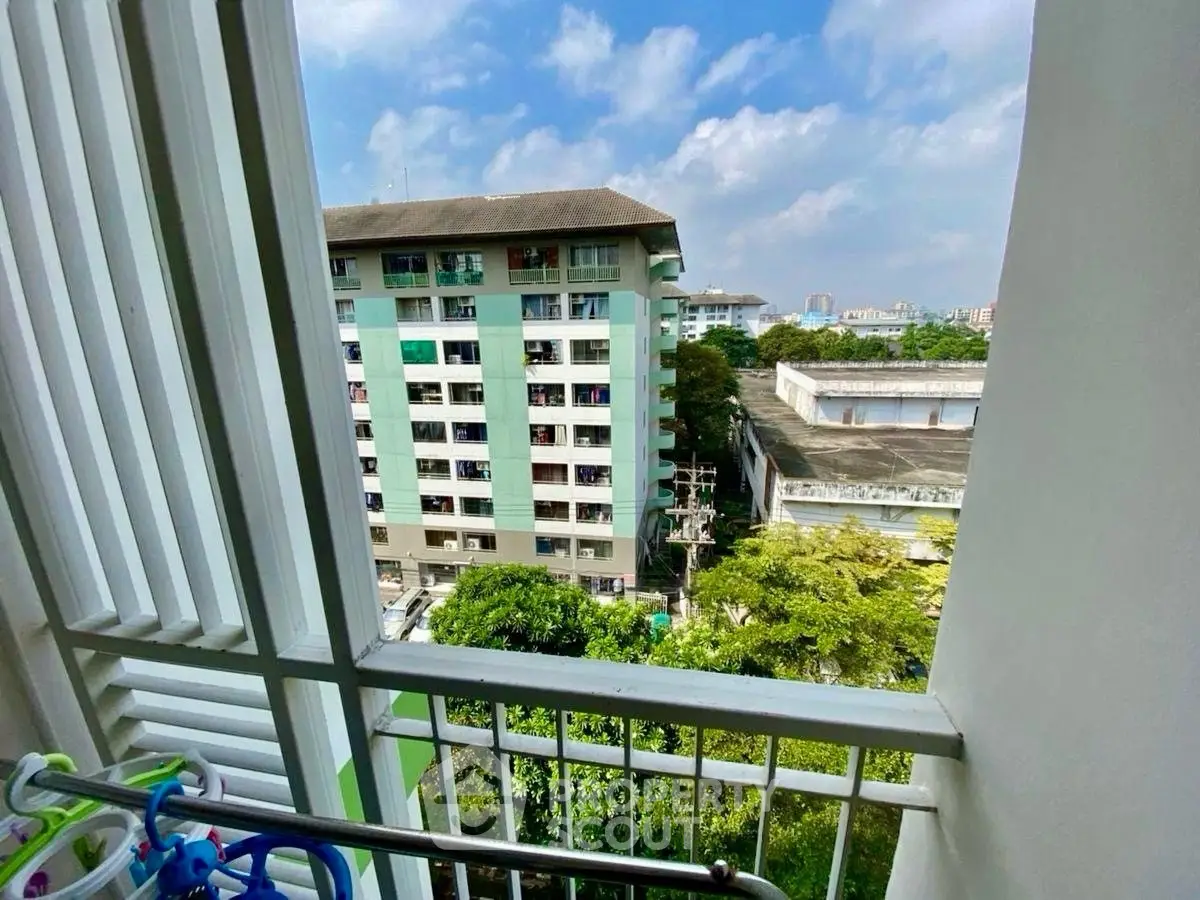 Scenic view from a balcony overlooking a residential building and lush greenery.