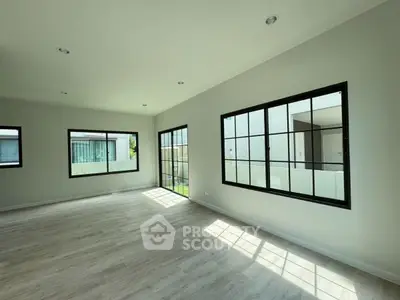 Spacious sunlit room with large windows and modern flooring in a contemporary home.