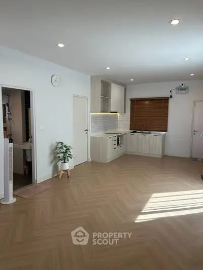 Modern open-plan kitchen with sleek cabinetry and wooden flooring, perfect for contemporary living.
