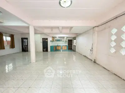 Spacious open-plan living area with tiled flooring and kitchen view.