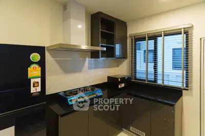 Modern kitchen with sleek black cabinets and gas stove, featuring a bright window view.