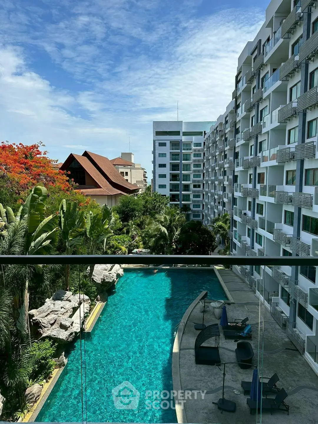 Luxurious apartment complex with stunning pool and lush greenery view.