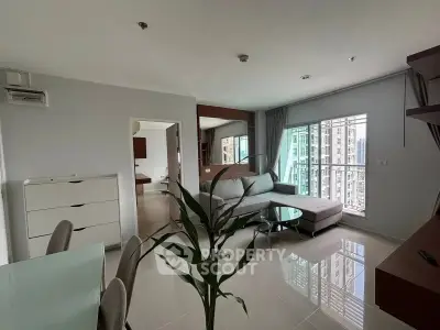 Modern living room with large windows and city view, featuring sleek furniture and open layout.