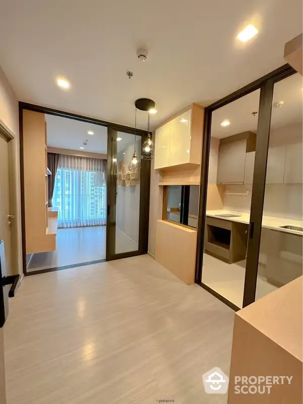 Modern apartment showcasing a seamless open layout with a spacious living area adjacent to a sleek kitchen, featuring contemporary lighting and large windows for ample natural light.