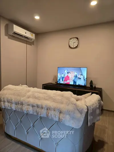 Cozy living room with plush sofa, wall-mounted TV, and air conditioning unit.