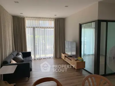 Modern living room with large window, stylish sofa, and sleek TV setup.