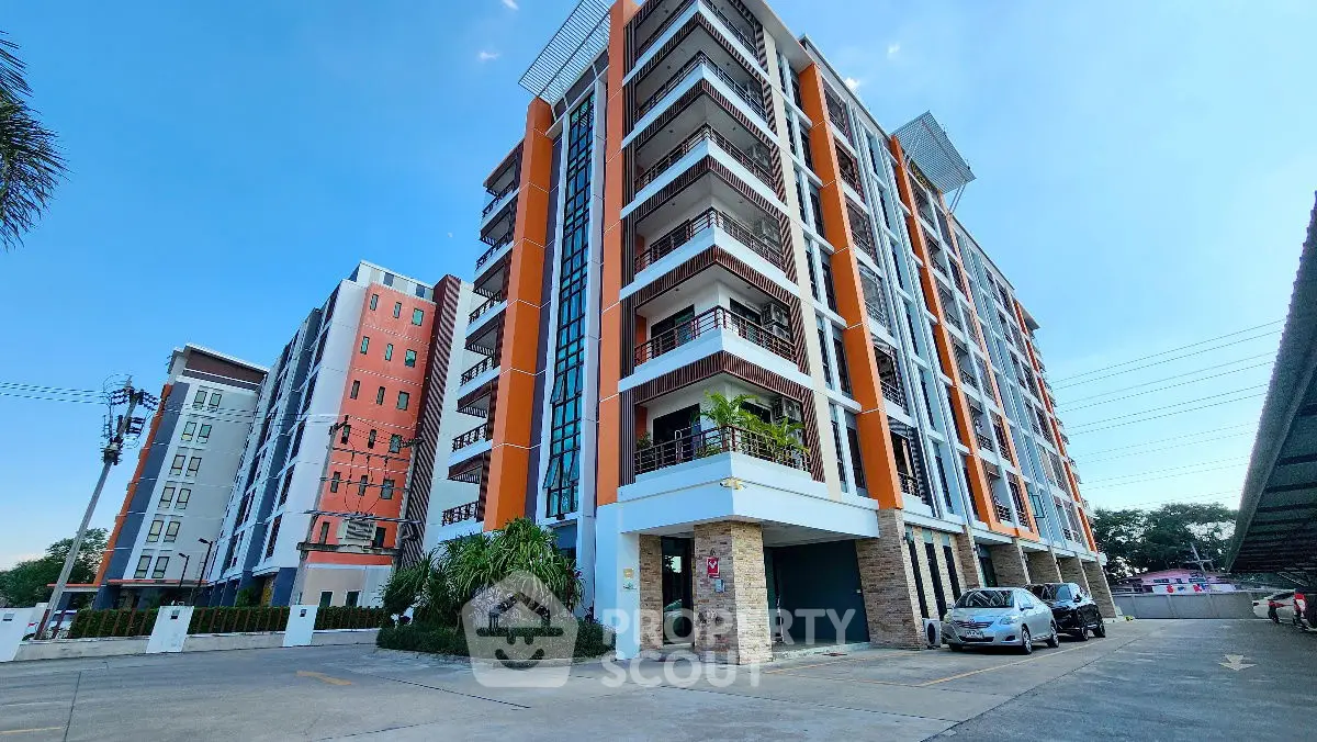 Modern multi-story apartment building with spacious balconies and parking area.