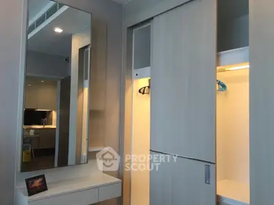 Modern bedroom with sleek built-in wardrobe and mirror reflecting a stylish interior design.