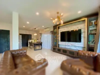 Luxurious living room with elegant decor and large TV, open layout to modern kitchen.