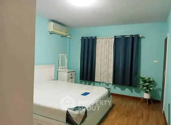 Cozy bedroom with blue walls, white furniture, and wooden flooring.