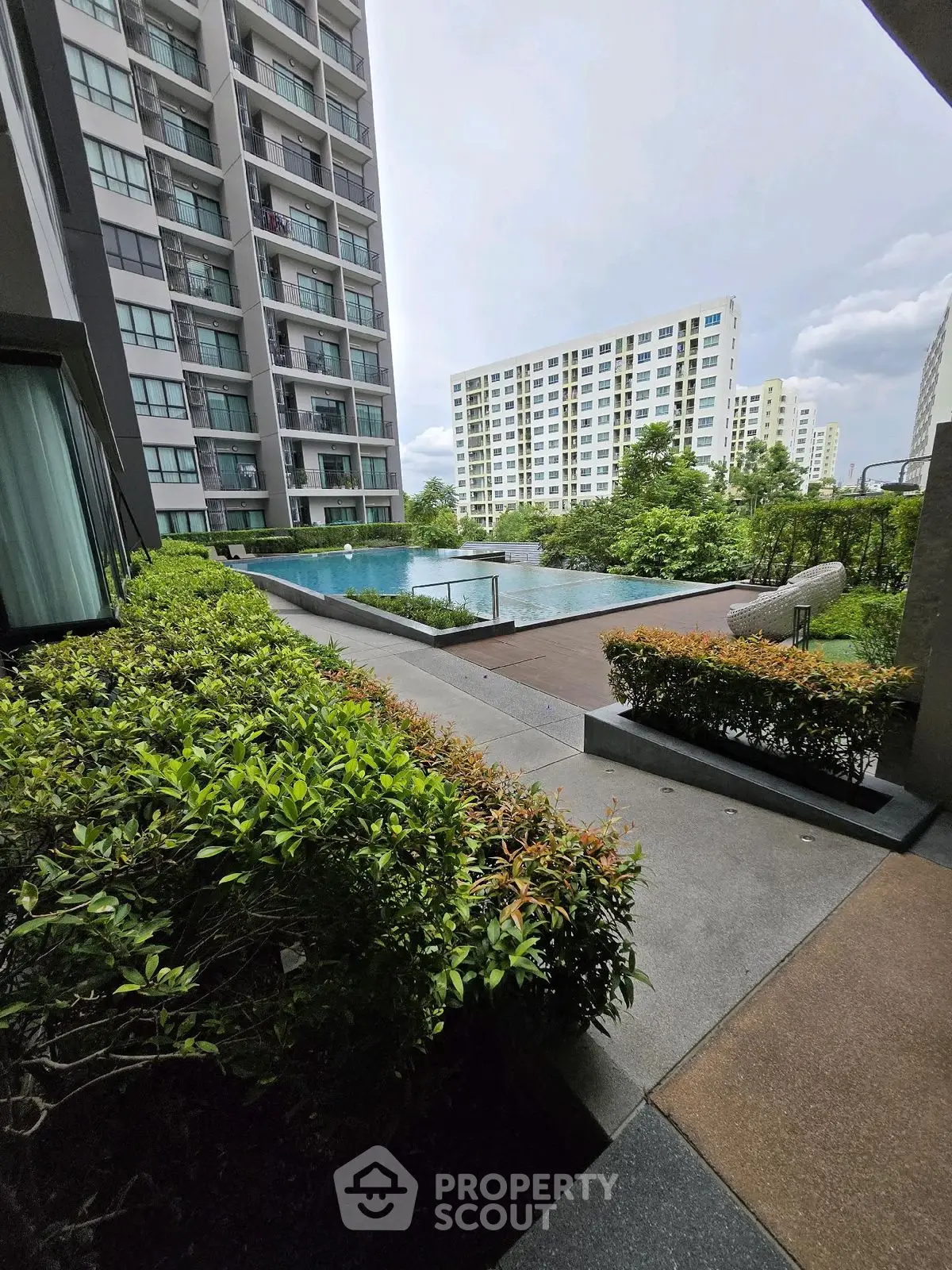 Modern apartment complex with lush greenery and inviting pool area.