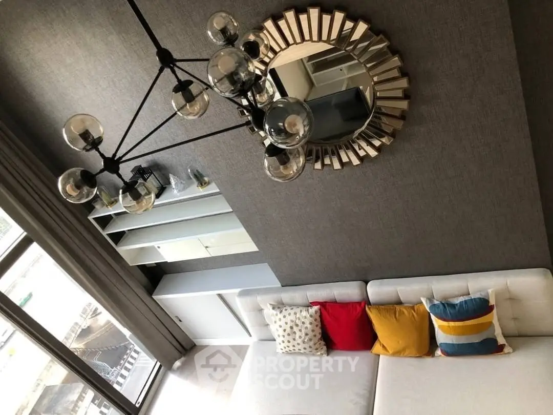 Stylish living room with modern chandelier and colorful cushions on a white sofa.