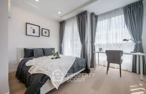 Modern bedroom with stylish decor and natural light, featuring a cozy bed and a sleek desk.