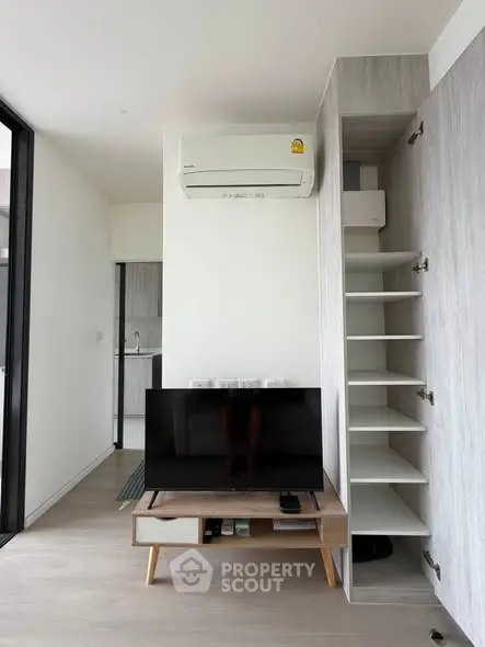 Modern living room with sleek TV stand, air conditioning, and open shelving in a bright apartment.