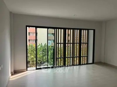 Spacious modern living room with large windows and balcony view.