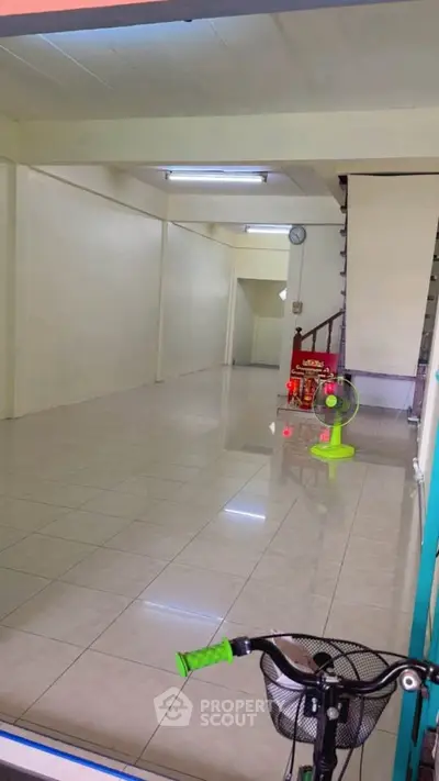 Spacious empty room with tiled flooring and staircase, ideal for customization.