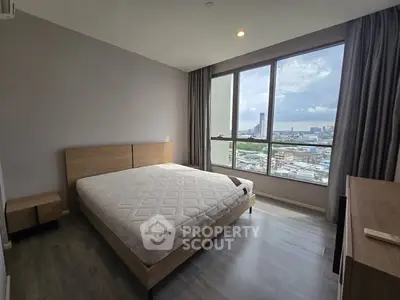 Spacious bedroom with large window offering stunning city views, modern furnishings, and ample natural light.