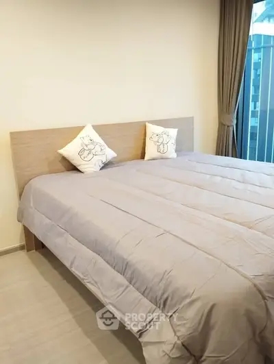 Cozy bedroom with modern decor and large window offering natural light.