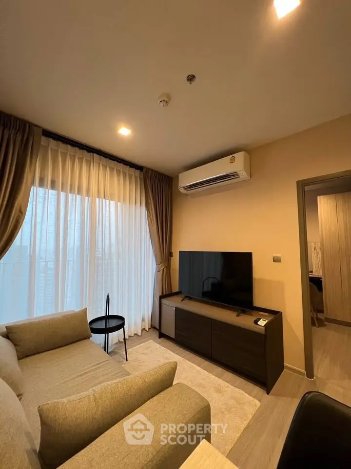 Modern living room with cozy sofa, flat-screen TV, and elegant curtains in a stylish apartment.