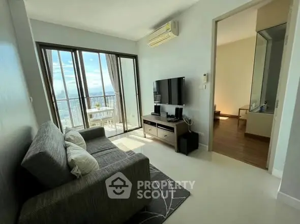 Modern living room with balcony and city view, featuring sleek furniture and natural light.