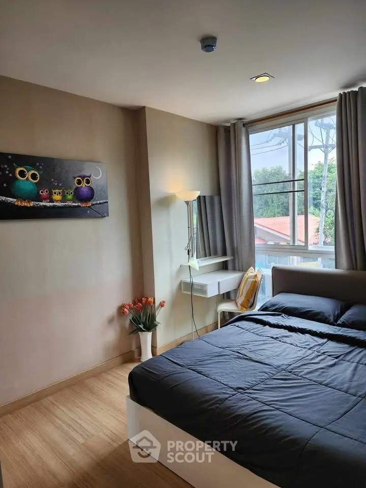 Cozy bedroom with large window and modern decor, featuring a comfortable bed and stylish artwork.