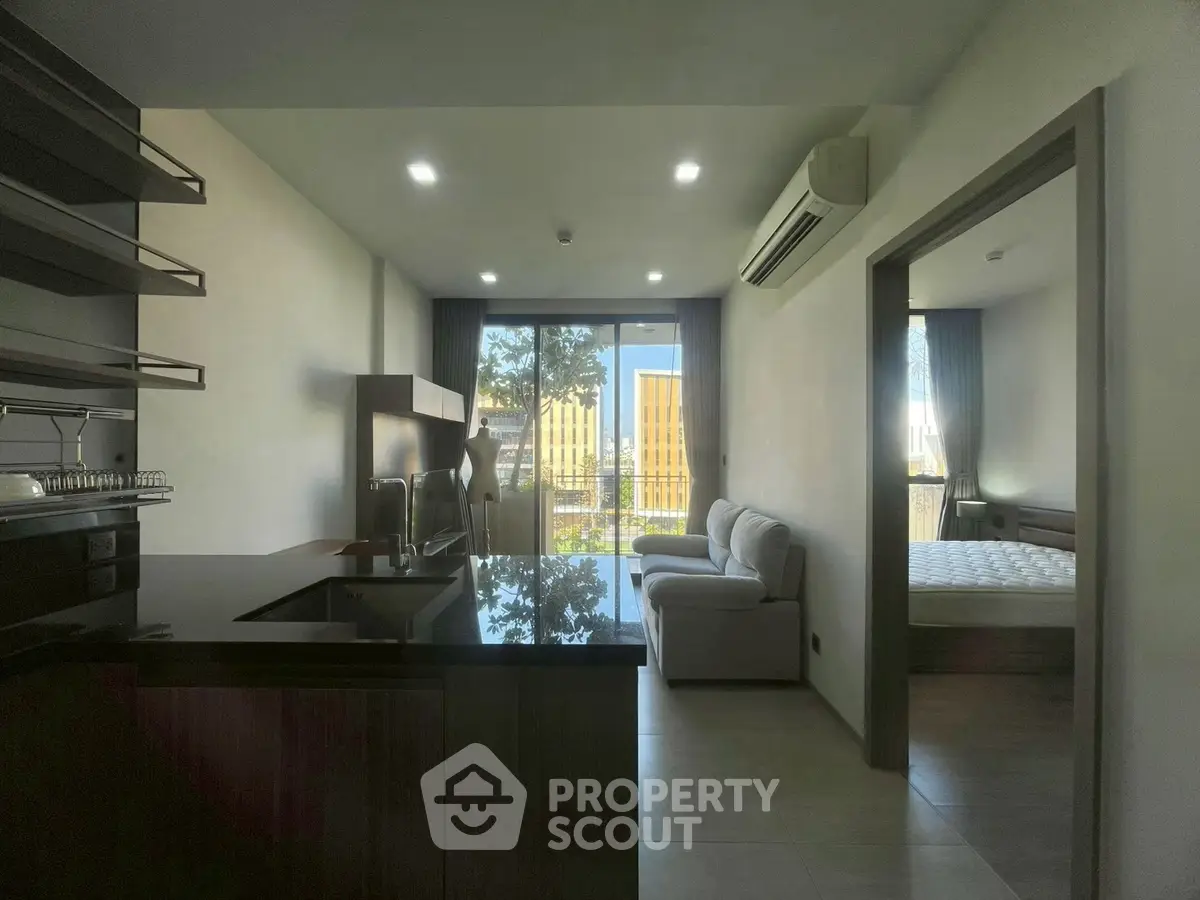 Modern apartment interior with open kitchen and cozy living area, featuring a balcony view.