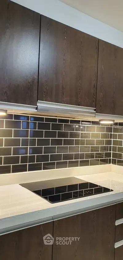 Modern kitchen with sleek dark wood cabinets and stylish black subway tile backsplash.