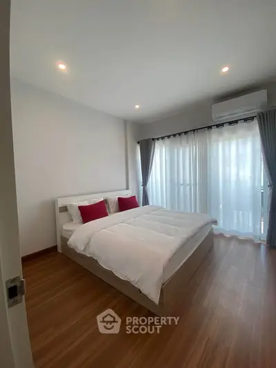 Spacious bedroom with modern decor and large windows for natural light