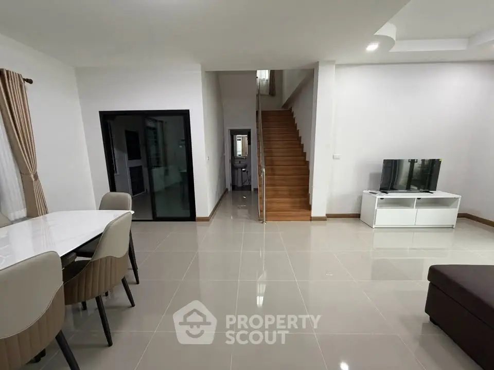 Spacious modern living room with elegant dining area and wooden staircase