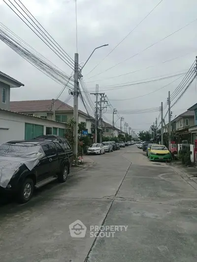 Charming suburban street view with parked cars and residential houses, ideal for family living.