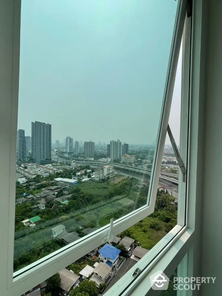 Stunning cityscape view from high-rise apartment window, showcasing urban skyline and greenery.