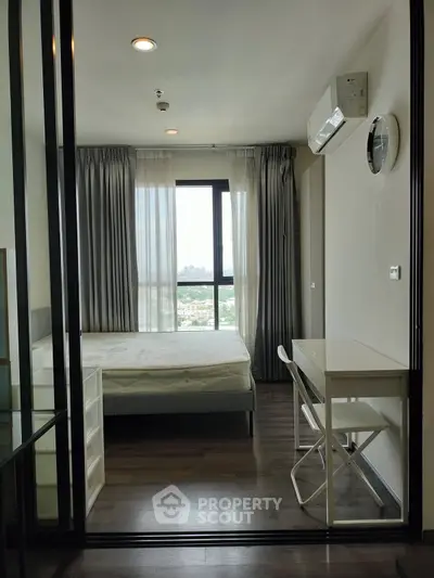 Modern bedroom with city view, featuring sleek furniture and large windows for natural light.