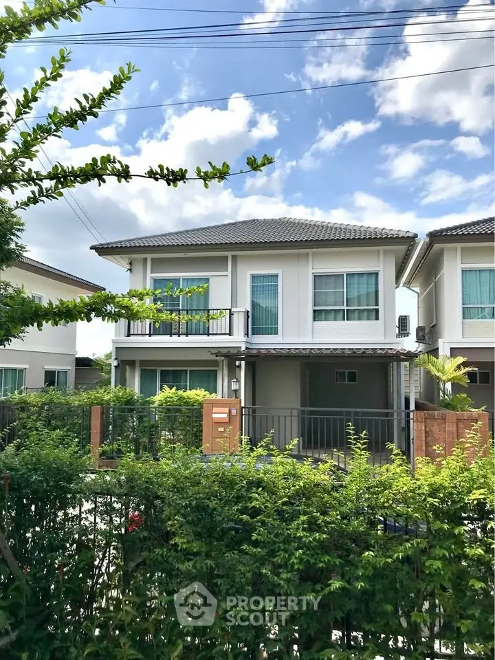 Charming two-story house with lush greenery and modern design in a serene neighborhood.