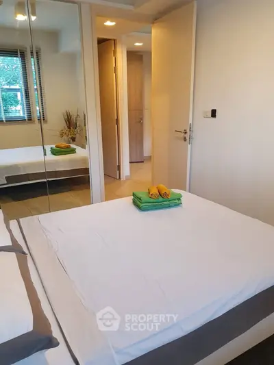 Cozy bedroom with mirrored closet and fresh linens in modern apartment.