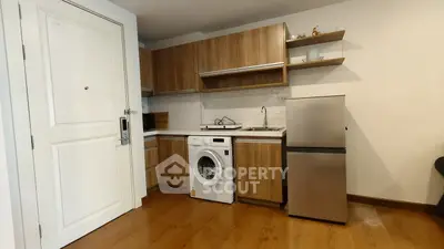 Modern kitchen with wooden cabinets, washing machine, and stainless steel fridge in a cozy apartment.