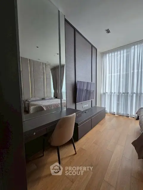 Modern bedroom with sleek design, featuring a wall-mounted TV and elegant furnishings.
