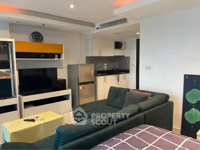 Modern living room with cozy sofa, TV, and compact kitchen area in open layout apartment.
