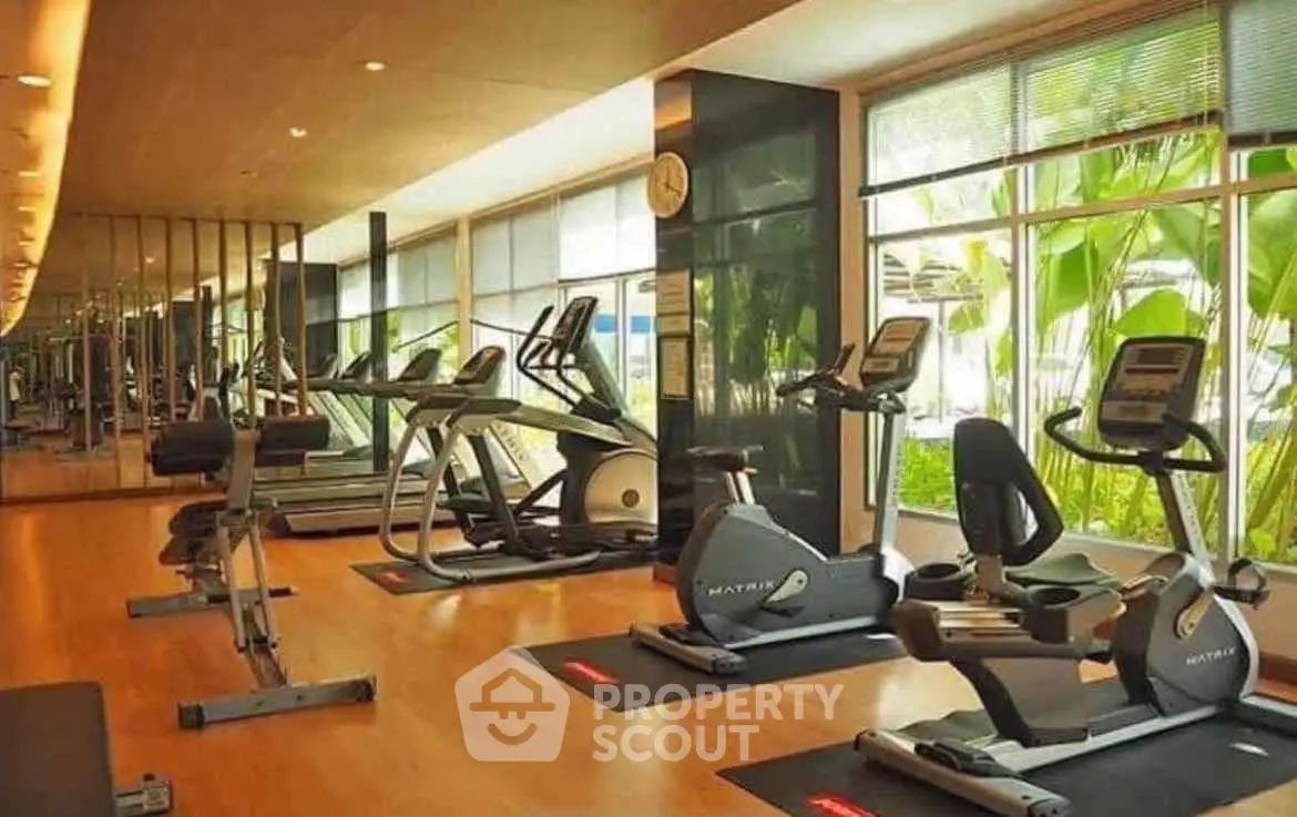 Modern gym with state-of-the-art equipment and large windows offering a lush garden view.